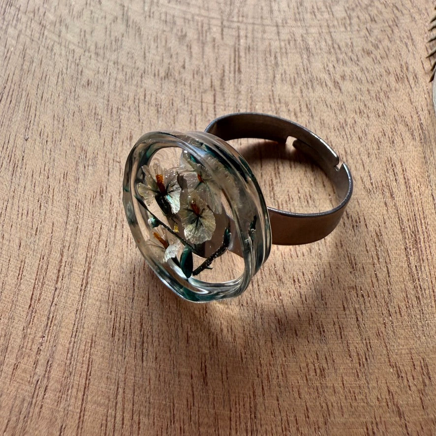 Vista superior de anillo de resina transparente con flores lilas en anillo Meulin.