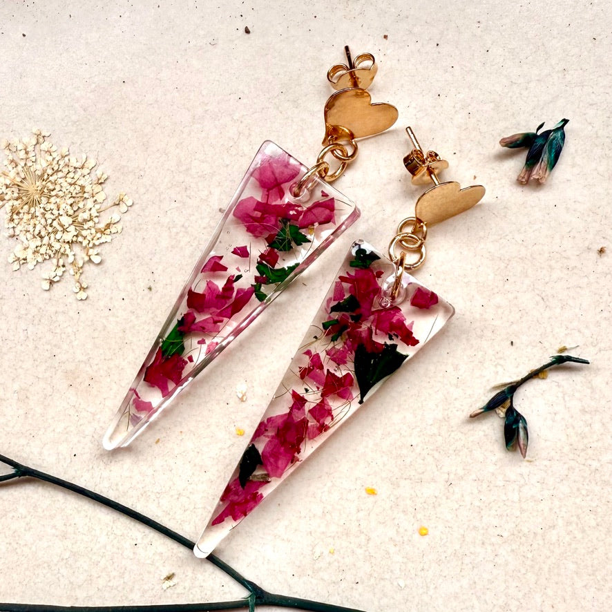 Par de aros Caldera, cápsula triangular con pétalos color rosado de hortensia. Broche con forma de corazón.