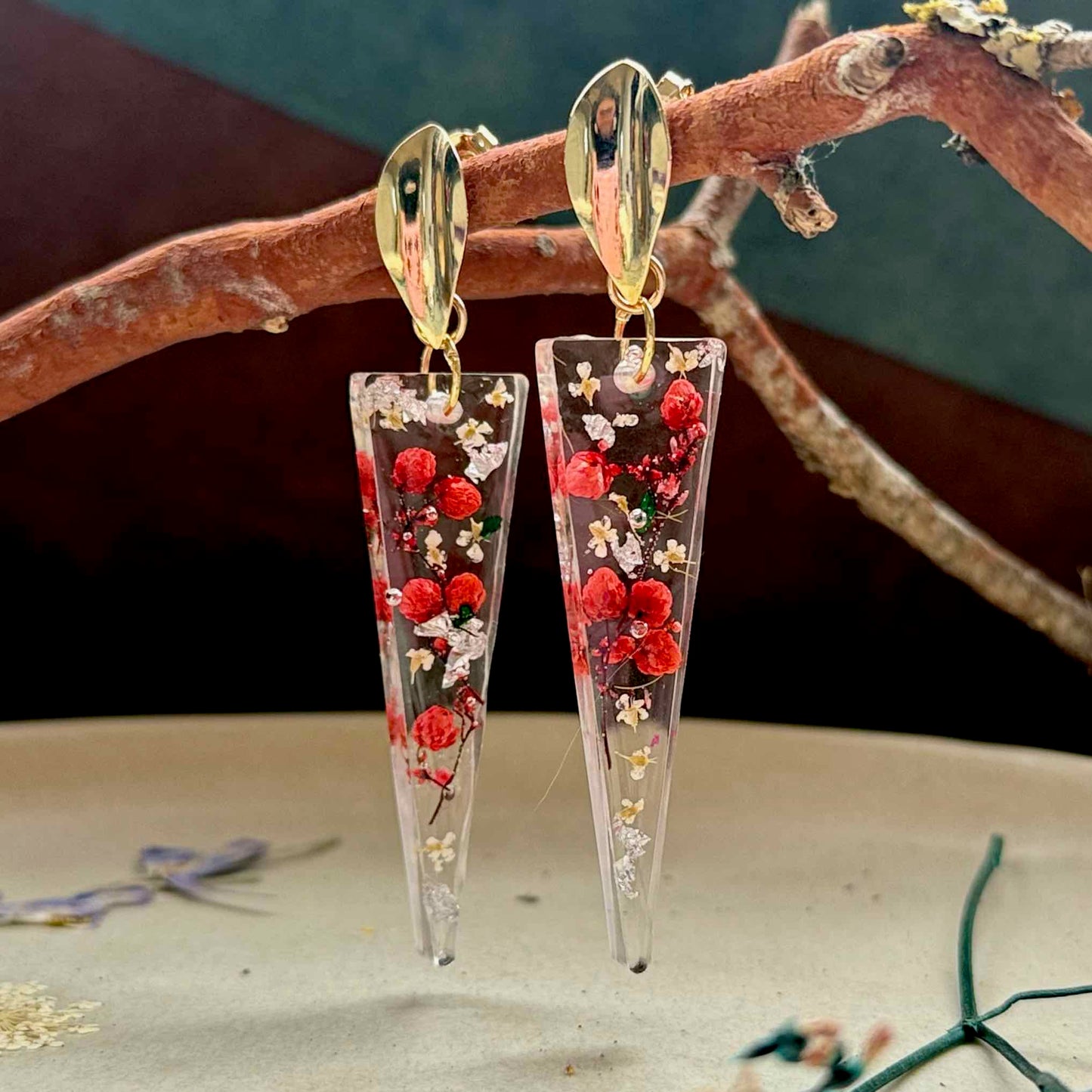 Par de aros Pucura, cápsula de resina triangular con flor de arroz roja encapsulada.