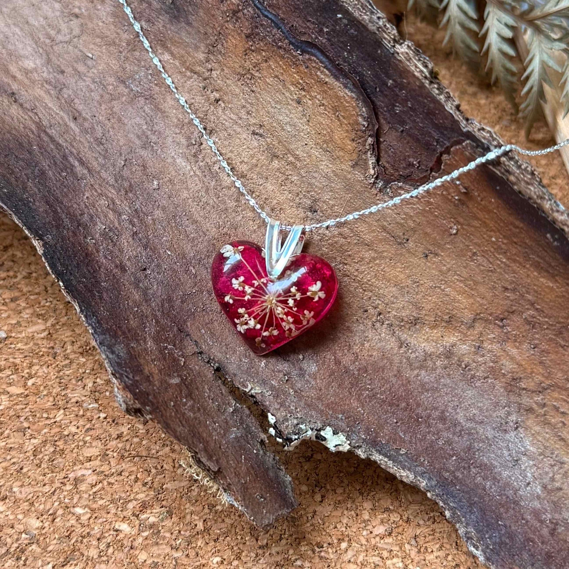 Collar Licán Ray con forma de corazón y cadena de plata 925, con pétalo de bugambilia y mini flor de cicuta.