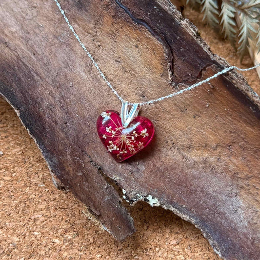 Collar Licán Ray con forma de corazón y cadena de plata 925, con pétalo de bugambilia y mini flor de cicuta.