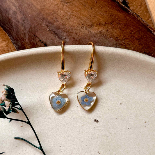 Par de aros Bolsón, pequeños marco de corazones bañados en oro que encapsula flor no me olvides.