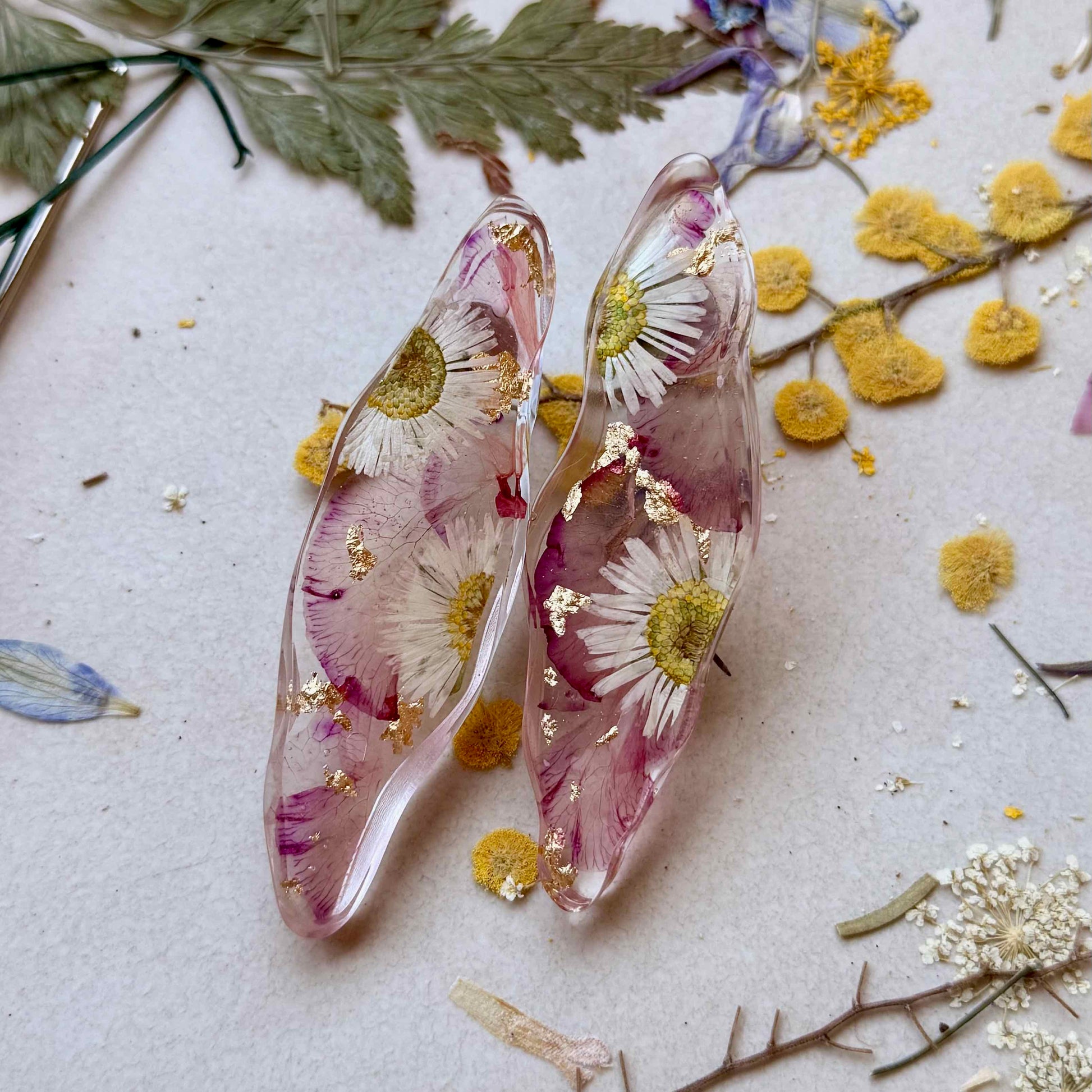 Par de aros Puerto Varas con pétalos rosados de flor adelfa, margaritas y detalles dorados.